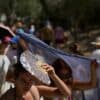 Dos turistas se cubren del sol con un panuelo y un abanico mientras avanzan en una fila de visitantes durante una ola de calor